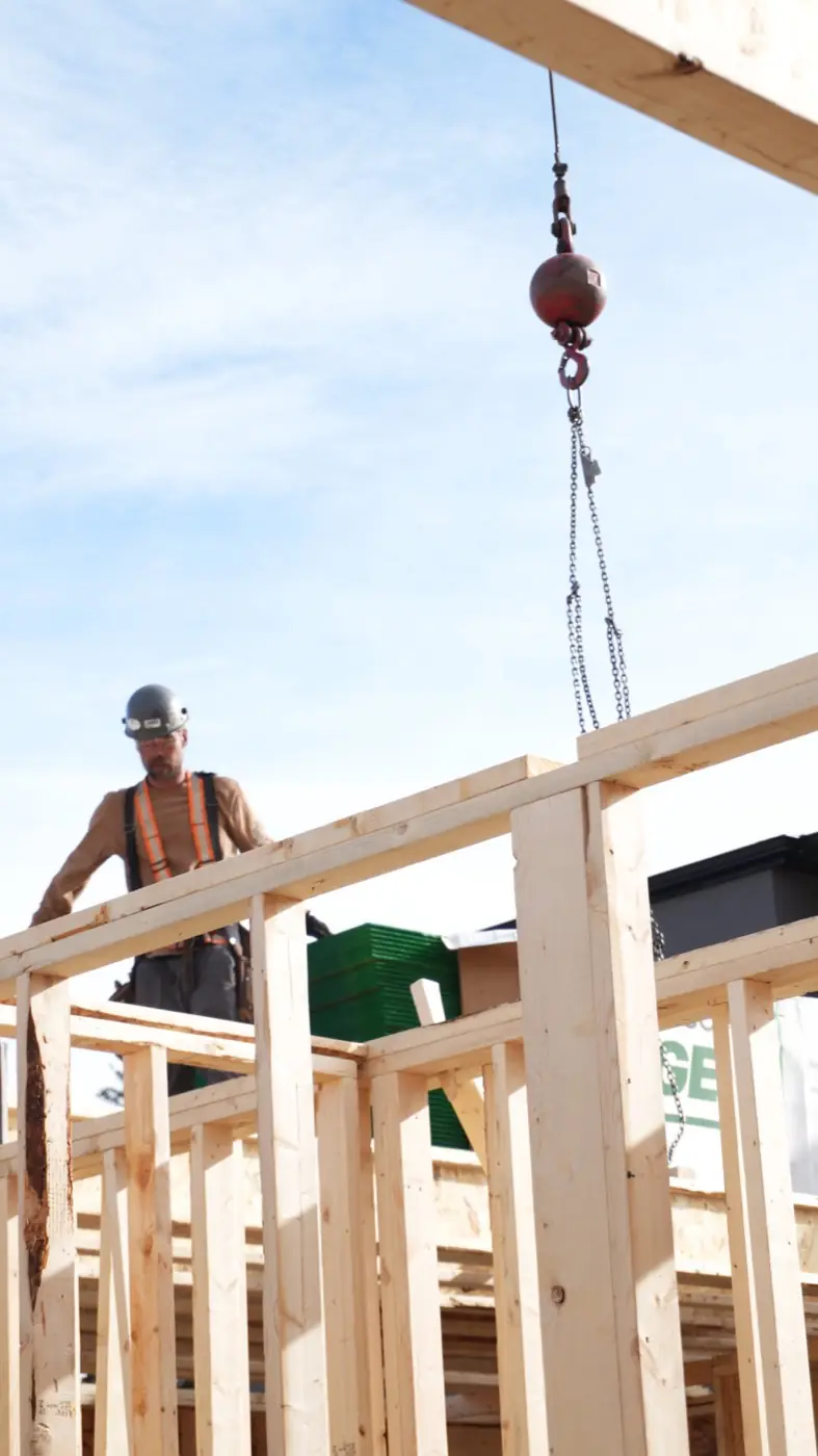 Crane lifting a framed wall panel into place on a Calgary build